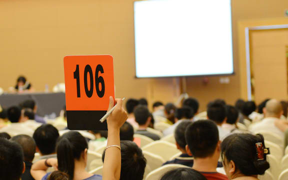 People holding auction paddle to buy from auction.