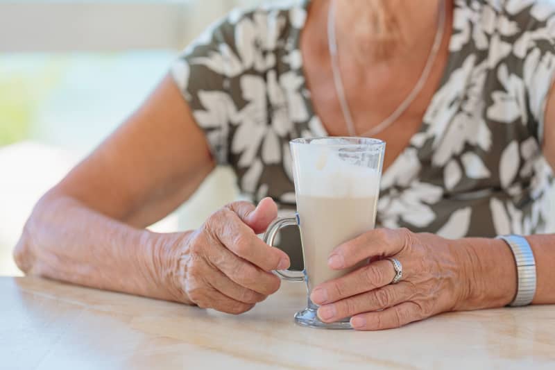 Cropped photo of stylish senior woman holding cup of coffee outdoors