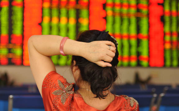 A concerned Chinese investor looks at prices of shares (red for price rising and green for price falling) at a stock brokerage house in Fuyang city, east China's Anhui province, 24 June 2016.