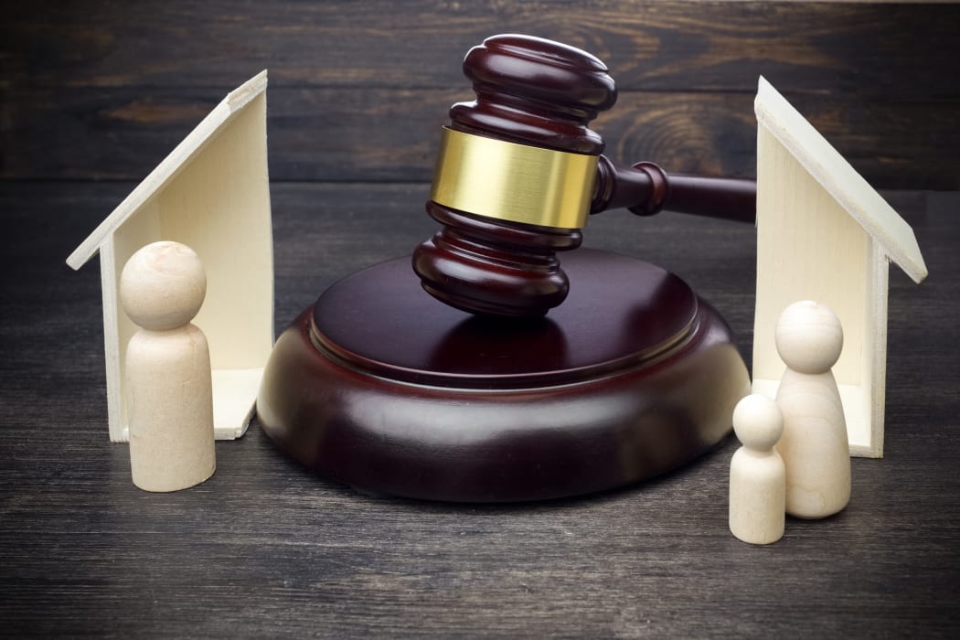 Gavel showing separation of family and house on dark wooden table