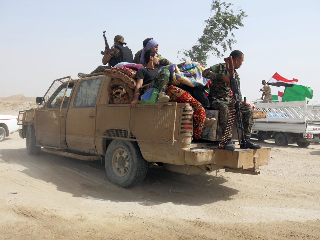 Fighters from a Shiite paramilitary units, known as Hashd Shaabi, sit on a military vehicle on the way to the frontline to fight against Islamic State.