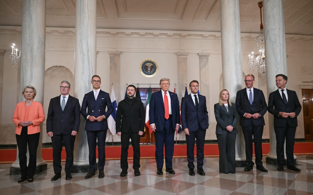 (L/R) European Commission President Ursula von der Leyen, British Prime Minister Keir Starmer, Finnish President Alexander Stubb, Ukrainian President Volodymyr Zelensky, US President Donald Trump, French President Emmanuel Macron, Italian Prime Minister Giorgia Meloni, German Chancellor Friedrich Merz and NATO Secretary-General Mark Rutte pose for a family photo in the Cross Hall of the White House in Washington, DC, on August 18, 2025. European leaders join Ukrainian President Volodymyr Zelensky in talks with US President Donald Trump on August 18, as they try to find a way to end Russia's offensive.  The leaders heading to Washington on Monday to appear alongside Zelensky call themselves the "coalition of the willing." (Photo by ANDREW CABALLERO-REYNOLDS / AFP)