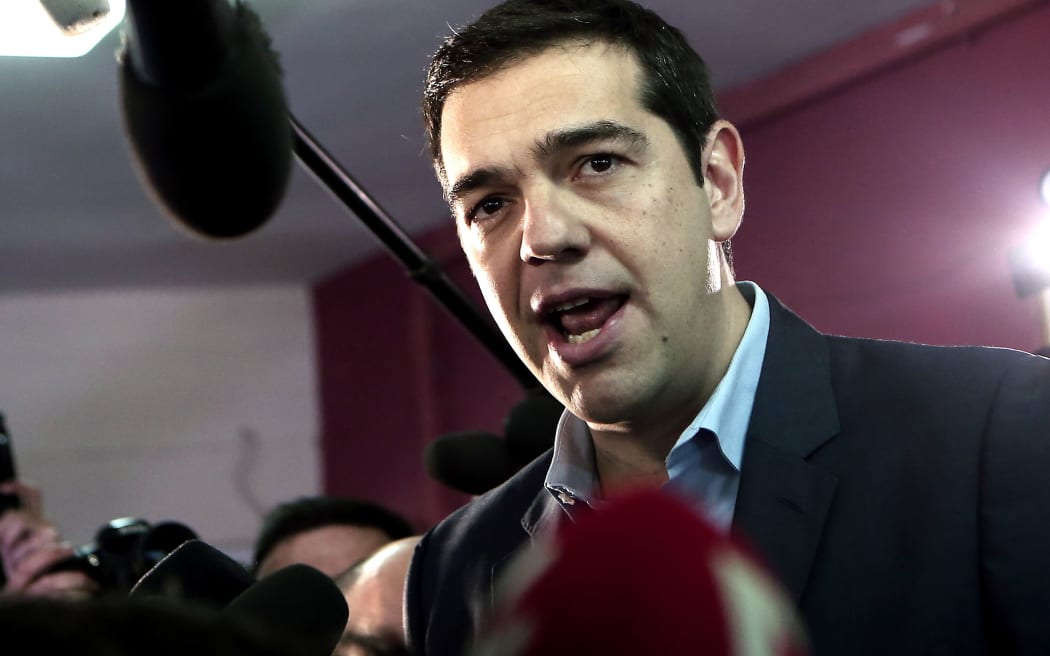 The leader of Greece's left-wing Syriza party Alexis Tsipras (C) talks to journalists after voting at a polling station in Athens in January 2015.