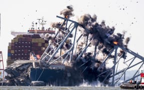 Crews conduct a controlled demolition of a section of the Francis Scott Key Bridge resting on the Dali container ship in Baltimore on May 13, 2024. The Francis Scott Key Bridge, a major transit route into the busy port of Baltimore, collapsed on March 26 when the Dali container ship lost power and collided into a support column, killing six roadway construction workers. (Photo by ROBERTO SCHMIDT / AFP)
