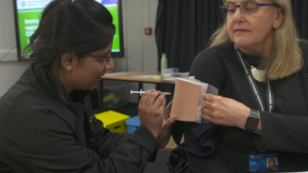 A trainee practices performing a vaccination.