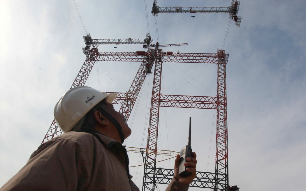 In this photograph taken on March 4, 2015, an Indian engineer gives instructions to a cable crane operator through a wireless set at the site of the under-construction world's highest railway bridge over the Chenab river in Kauri, in northern Jammu and Kashmir state.  Indian engineers are toiling in the Himalayas to build the world's highest railway bridge which is expected to be 35 metres taller than the Eiffel Tower when completed by 2016 and which will link sections of the spectacular mountainous region of India's northern Jammu and Kashmir state.  AFP PHOTO / RAKESH BAKSHI (Photo by rakesh bakshi / AFP)