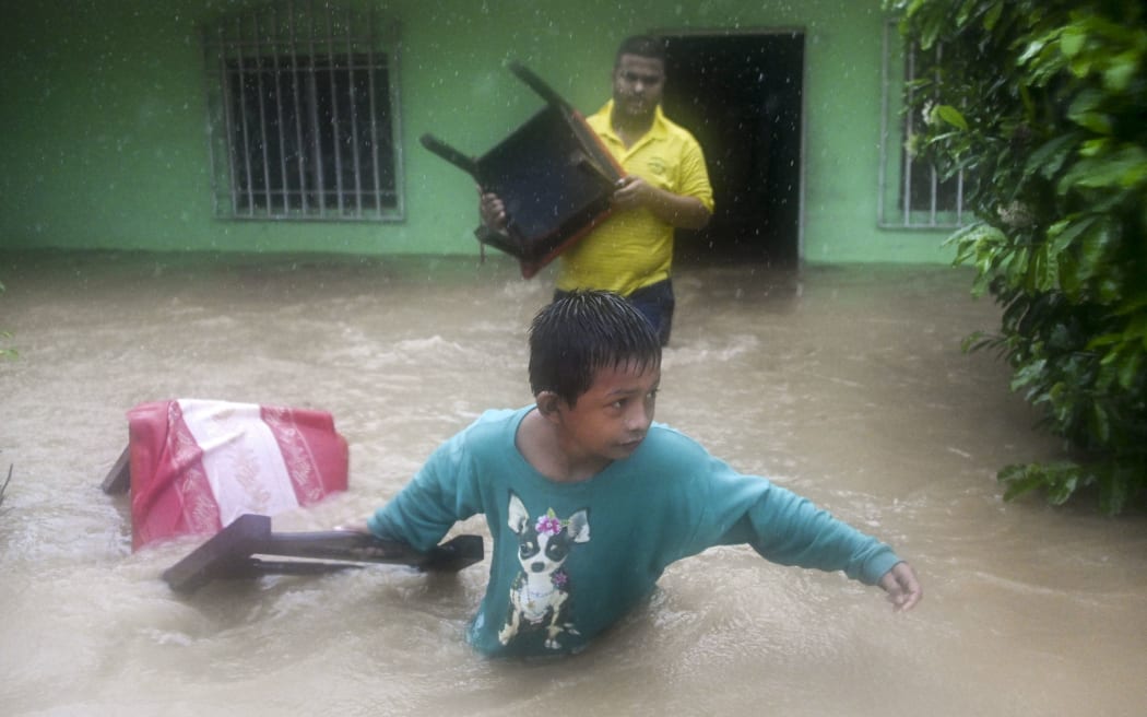 A boy and a man save chairs from a flooded house due to the heavy rains caused by Hurricane Eta, now degraded to a tropical storm, in Puerto Barrios, Izabal 310 km north Guatemala City on November 5, 2020.