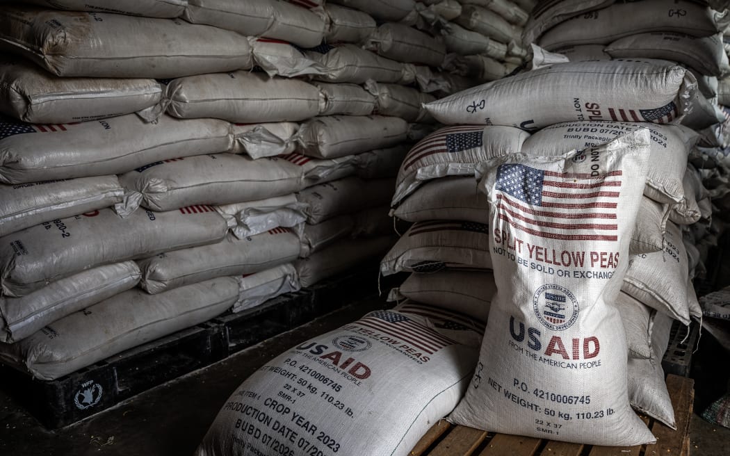 Sacks of the final batches of yellow peas delivered by the now-dismantled United States Agency for International Development (USAID) are stacked in a storage room during a food distribution for newly arrived Congolese refugees at the Cishemere Transit Center near Buganda, on May 6, 2025. Since January 2025, more than 71,000 people fleeing ongoing violence in the eastern part of the Democratic Republic of Congo have crossed into Burundi, its largest refugee influx in decades, UN says. In overcrowded camps settled in one of the poorest country in the World, deepening funding crisis threatens critical aid including significantly reduced food assistance, raising fears of violence. (Photo by Luis TATO / AFP)