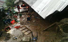 Villagers attempt to salvage their belongings from a house damaged in the landslide.