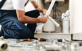 Cropped photo of a handsome young man plumber work in uniform indoors.