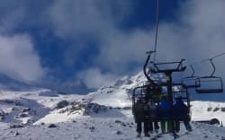 Skiers on a chairlift at Turoa ski field.