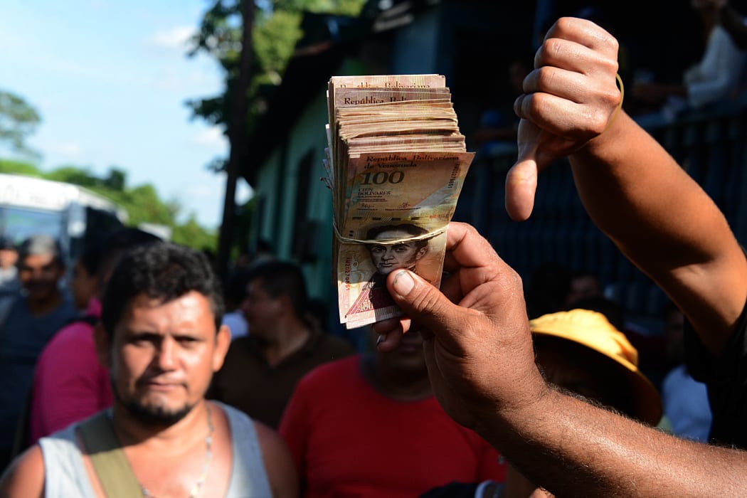 People hold up newly worthless 100-bolivar notes during a protest over lack of cash in the country.