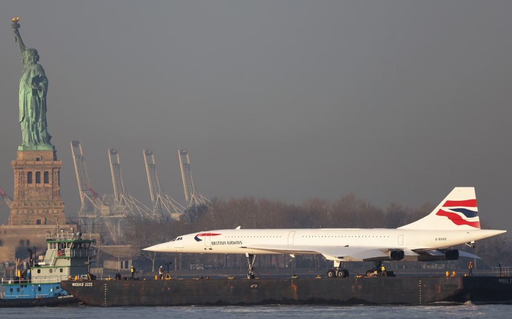 NEW YORK, NEW YORK - MARCH 14: A retired British Airways Concorde supersonic airliner is moved by a barge past the Statue of Liberty on the Hudson River on March 14, 2024 in New York City. The Concorde, one of a fleet of seven once owned by British Airways, departed the Weeks Marine in Jersey City, N.J. for its return to the Intrepid Museum following a months-long restoration project at the Brooklyn Navy Yard.  (Photo by Michael M. Santiago/Getty Images)