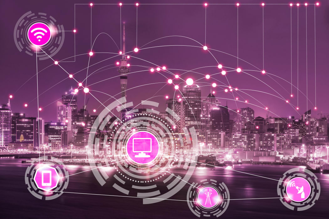 Smart city wireless communication network with graphic showing concept of internet of things ( IOT ) and information communication technology ( ICT ) against modern city buildings in the background.