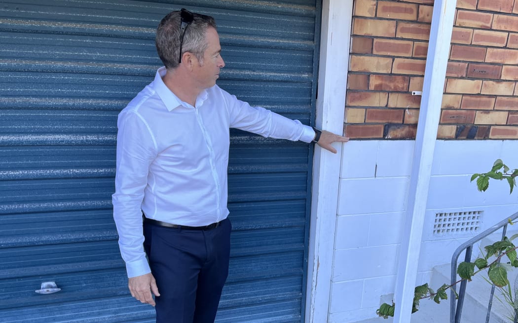 Nick Brown stands in front of a garage door indicating the floor level on a single-storey brick house