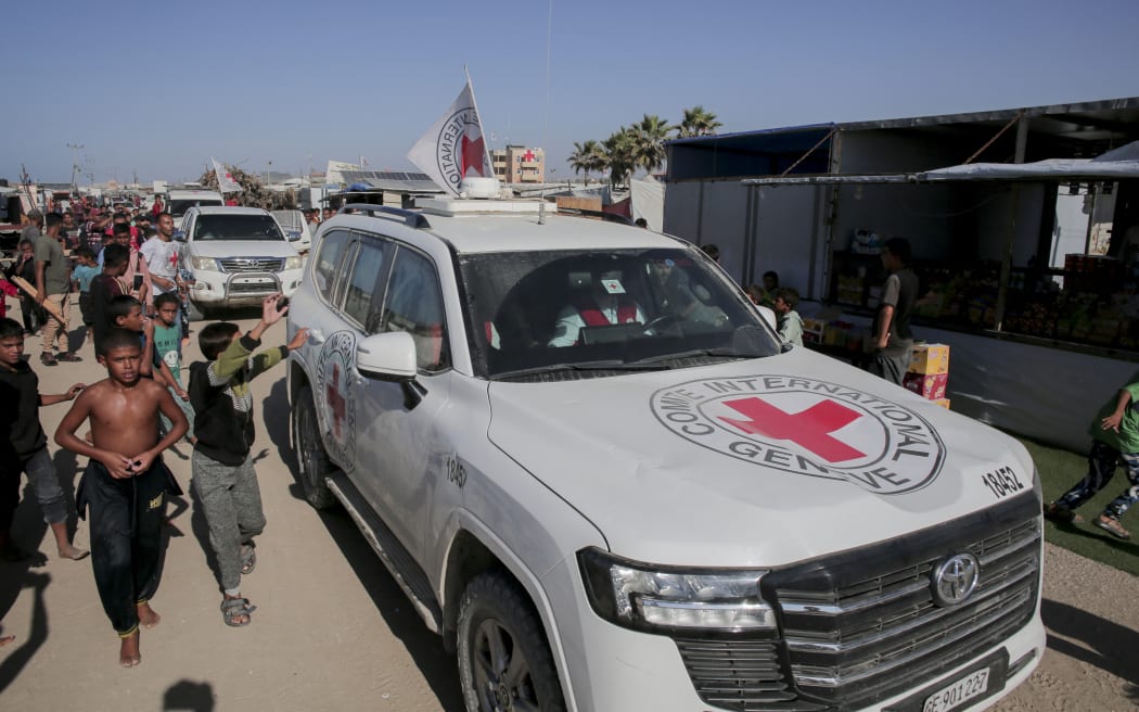 People gather around vehicles of the International Committee of the Red Cross (ICRC) in Khan Yunis, southern Gaza Strip, on October 26, 2025. Search operations are underway in the Gaza Strip to locate and recover the bodies of Israeli captives as part of the cease-fire and prisoner-hostage exchange deal between Hamas and Israel. Representatives from Hamas’ armed wing, the Izz al-Din al-Qassam Brigades, and the ICRC met in Khan Yunis to coordinate the recovery efforts. (Photo by Abdelrahman Rashad / Middle East Images via AFP)