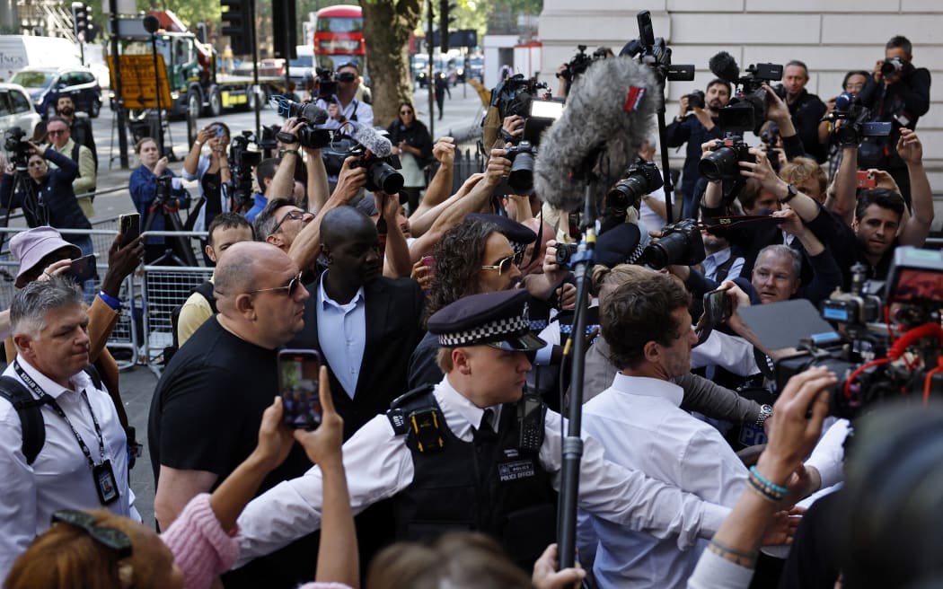 Surrounded by members of the media, British actor and comedian Russell Brand (C) arrives at Westminster Magistrates Court in London on May 2, 2025. Brand has been charged with rape and a number of other sexual offences alleged to have taken place between 1999 and 2005 involving four women. (Photo by BENJAMIN CREMEL / AFP)