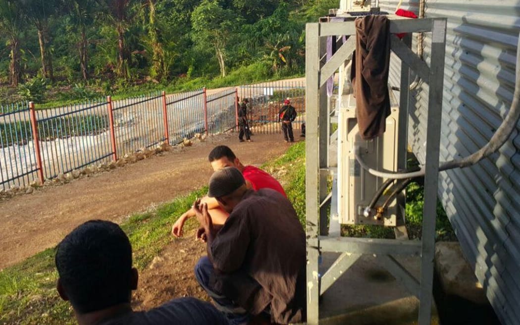 Refugees watch the action unfolding at the gate of Hillside Haus.