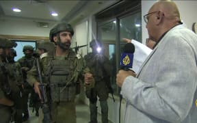 An image grab from footage distributed by the Doha-based Al-Jazeera TV on September 22, 2024 shows an Israeli soldier speaking with Walid Al-Omari, bureau chief of Al Jazeera in Jerusalem and Ramallah, upon entering Al Jazeera's office in Ramallah, in the West Bank to issue a 45-day closure order on September 21. (Photo by AL JAZEERA / AFP) / RESTRICTED TO EDITORIAL USE - MANDATORY CREDIT "AFP PHOTO / AL-JAZEERA" - NO MARKETING NO ADVERTISING CAMPAIGNS - DISTRIBUTED AS A SERVICE TO CLIENTS