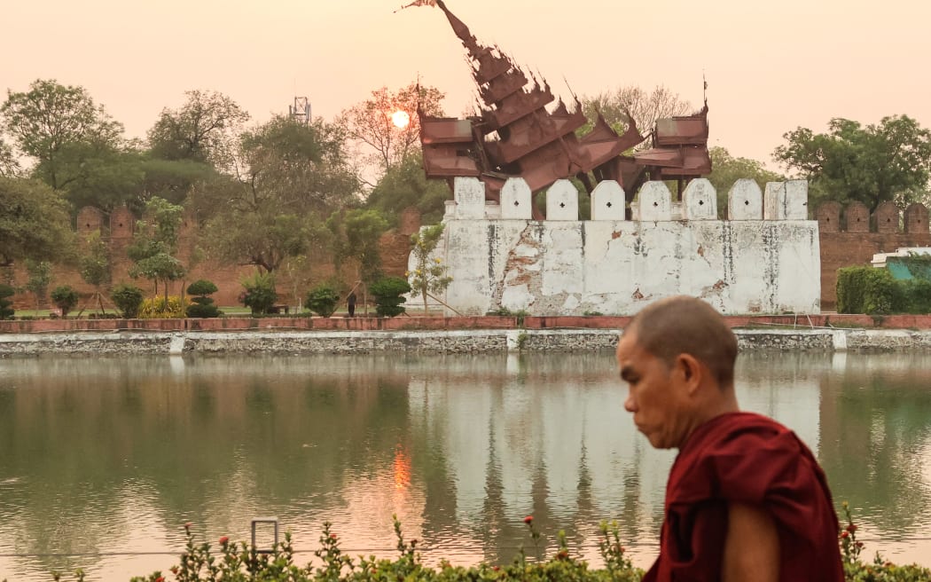A Buddhist monk walks past the damaged Mandalay Palace during sunset in Mandalay on March 31, 2025, three days after the deadly Myanmar earthquake. Myanmar declared a week of national mourning on March 31 for the country's devastating earthquake, as the death toll passed 2,000 and hopes faded of finding more survivors in the rubble of ruined buildings. (Photo by Sebastien BERGER / AFP)