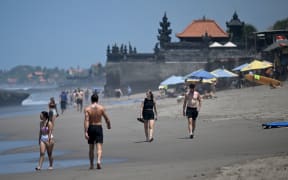 Tourists walk on a beach in Canggu, Badung regency on Bali island.