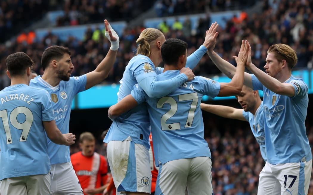 Manchester City players celebrate a goal against Luton Town.