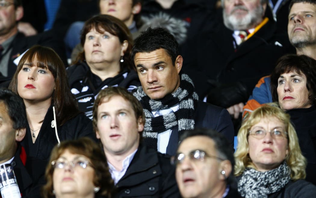 A dejected looking injured All Black Dan Carter watches from the stands.