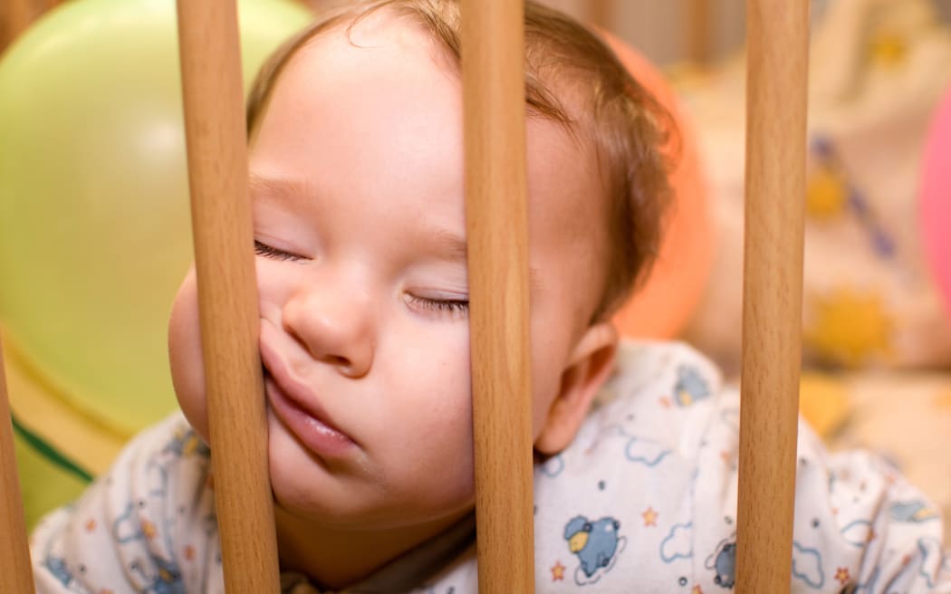 Baby sleeps with funny face in the playpen