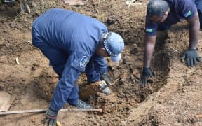 Solomon Islands police officers digging up WWII shells at Gilbert Camp in Honiara.
