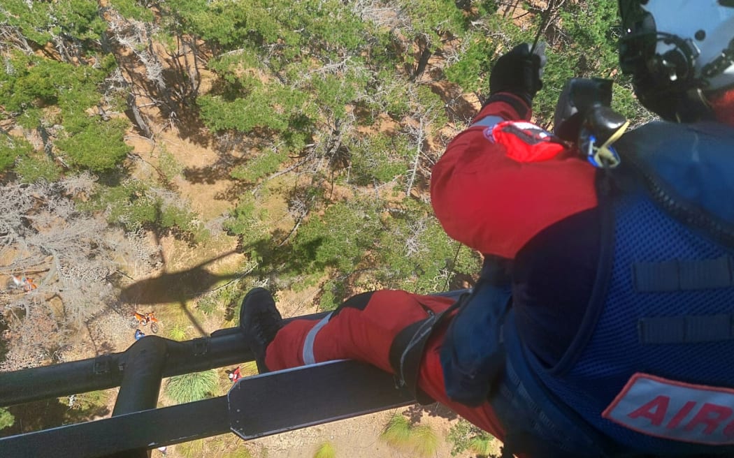 An Auckland Rescue paramedic about to be lowered into Woodhill Forest. The crashed bike can be seen below.