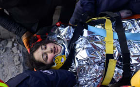 A 12-year-old Syrian girl, Cudi, is evacuated by rescuers from the rubble of a destroyed building in Hatay, on February 12, 2023, after a 7.8-magnitude earthquake struck the country's south-east. - The death toll from a massive earthquake that hit Turkey and Syria climbed to more than 20,000 on February 9, 2023, as hopes faded of finding survivors stuck under rubble in freezing weather. (Photo by Yasin AKGUL / AFP)