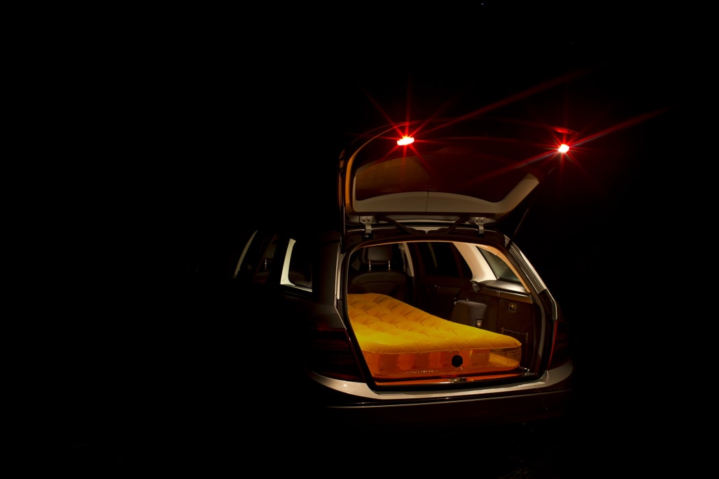 A mattress in the back of a station wagon at night to illustrate people sleeping in cars or vans.
