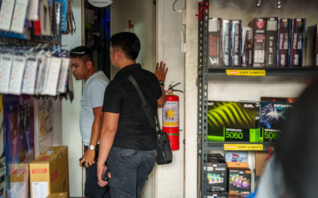 Plain-clothed Philippines police getting CCTV footage copied.