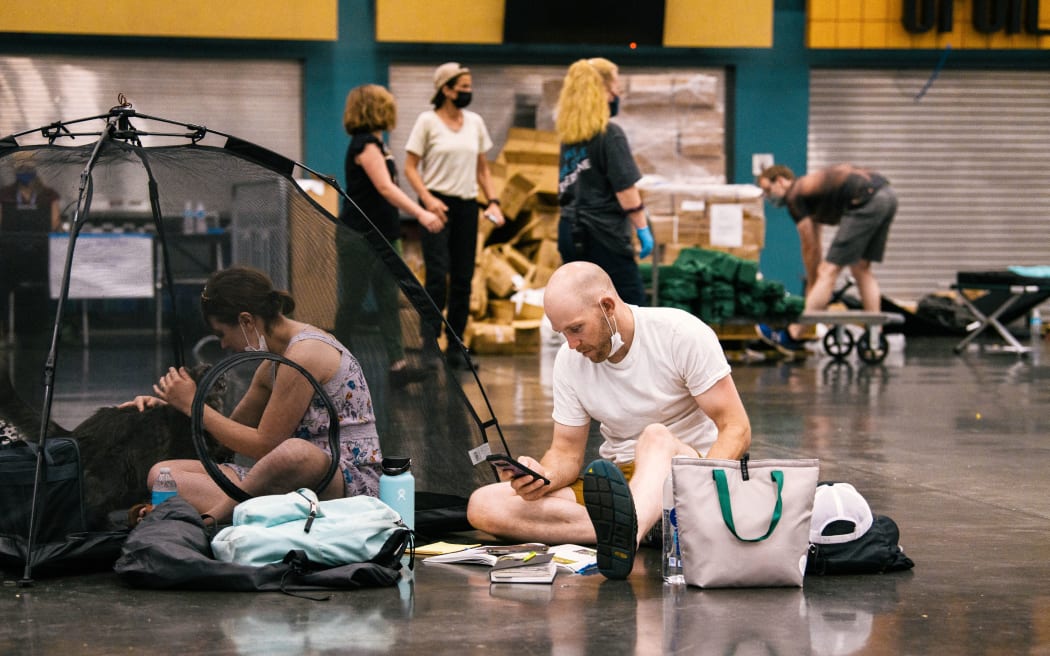 People and their pets rest at the Oregon Convention Center cooling station in Oregon, Portland on 28 June as a heatwave moves over much of the United States.