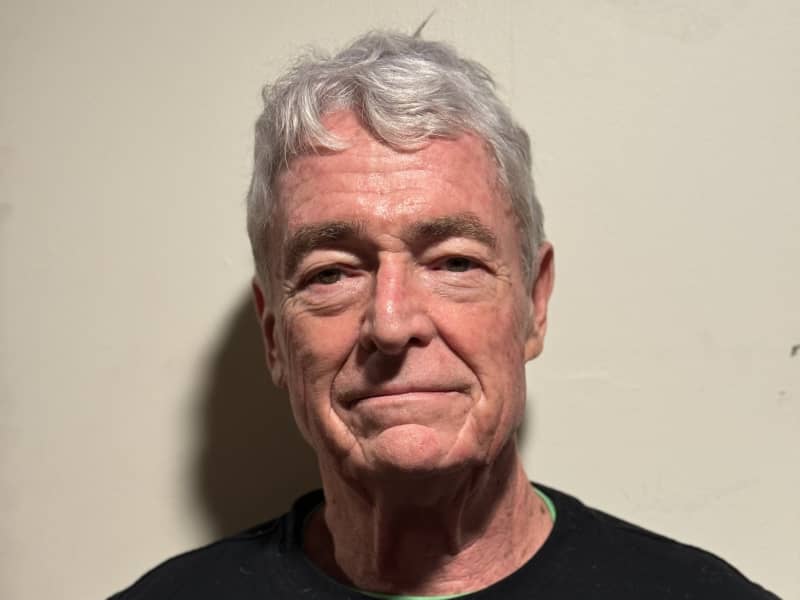 John Koten smiles slightly and seems to have clear skin.