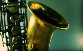 Artistic shot of a tenor saxophone on a blue-green background