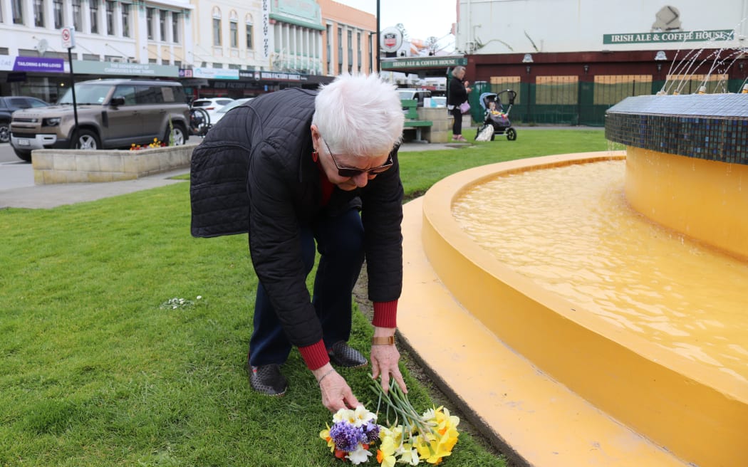 Dorothy Galloway places flowers in remembrance of the Queen at the fountain outside the cathedral.