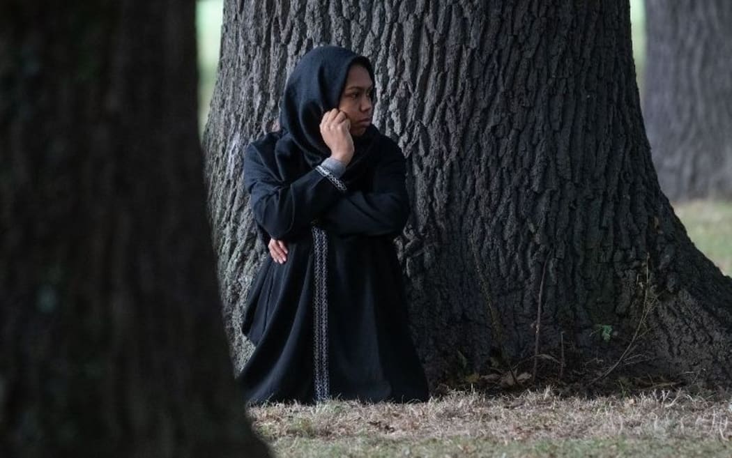 A woman sits quietly across the road from the Al Noor mosque.