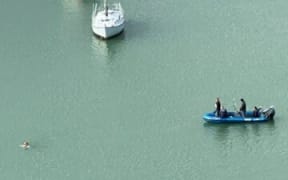 Police, in an inflatable boat, pursue a man through the water in the Bay of Islands.