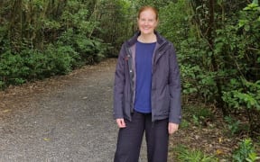 A woman standing in a forest area.