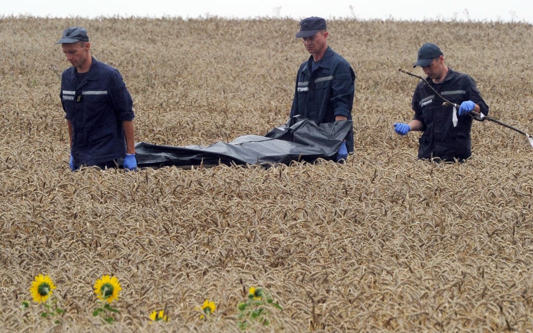 Ukrainian rescue workers carry the body of a victim on a stretcher through a wheat field at the site of the crash.