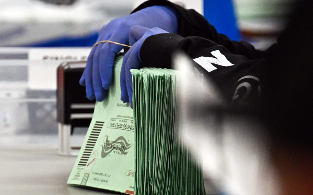 An election worker bundles envelopes inside the Maricopa County Tabulation and Election Center (MCTEC) on Election Day, November 5, 2024 in Phoenix, Arizona. - Pairs of election workers from different political parties open mail-in ballot envelopes containing voted ballots after they completed signature verification. (Photo by Patrick T. Fallon / AFP)