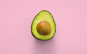 an avocado with a pink background