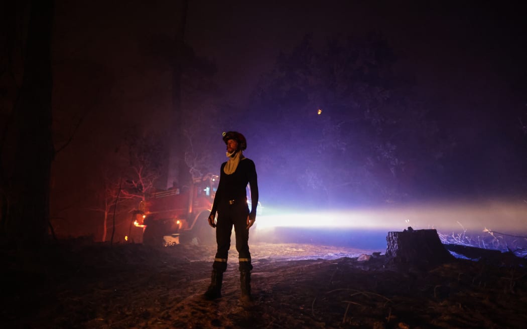 A firefighter stands as a wildfire spreads in the area close to the beach of Cazaux lac, near La Teste-de-Buch, southwestern France, on July 15, 2022. - In a context of strong heat on the southern half of the country, the firemen still face two aggressive forest fires in Gironde, with more than 5.000 hectares burned and more than 10.000 people evacuated since July 12, 2022, and fight from now on a "virulent" fire near Avignon. (Photo by THIBAUD MORITZ / AFP)
