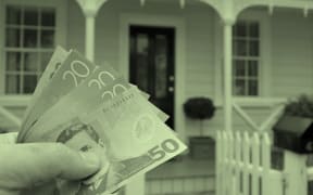 In the foreground of the bottom left corner of the image, a hand holds five New Zealand banknotes. In the background is a wooden home. The image has a green wash over it.