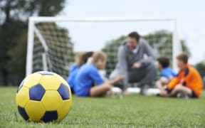 Children with a teacher and a soccer ball in the foreground