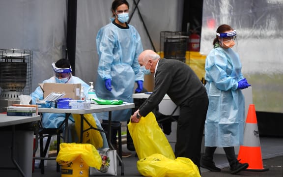 A courier collects swabs taken at a drive-through testing clinic in Melbourne