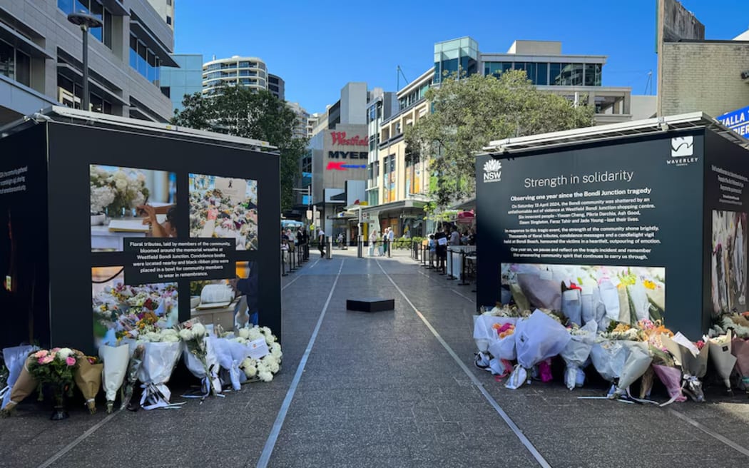 A commemorative stand and floral tributes one year after the Bondi Junction stabbing attack at Oxford Street Mall. (ABC News: Sean Tarek Goodwin)
