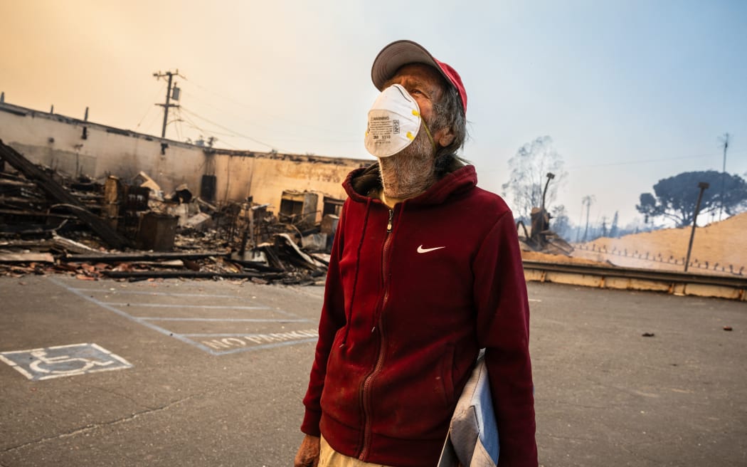 Altadena, California resident David Slater,81, looks at the damage from the Eaton Fire in Altadena, California, on January 9, 2025. Wildfires threatened to engulf parts of Hollywood on January 9 as a growing number of blazes raged across Los Angeles, forcing over 100,000 people to flee their homes and claiming at least five lives. (Photo by Zoë Meyers / AFP)