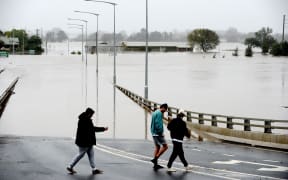 People walk over an old Windsor Bridge along the overflowing Hawkesbury River in the northwestern Sydney suburb of Windsor on 6 July, 2022.